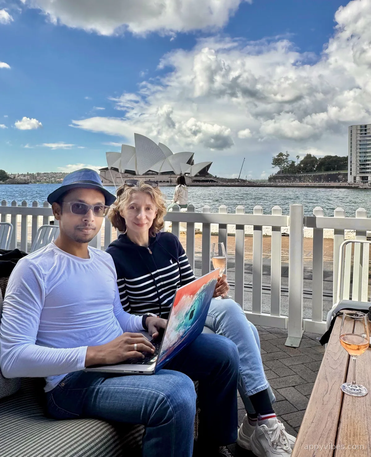 Dileep and Inga working on a laptop by Sydney Harbour, with the Opera House behind them
